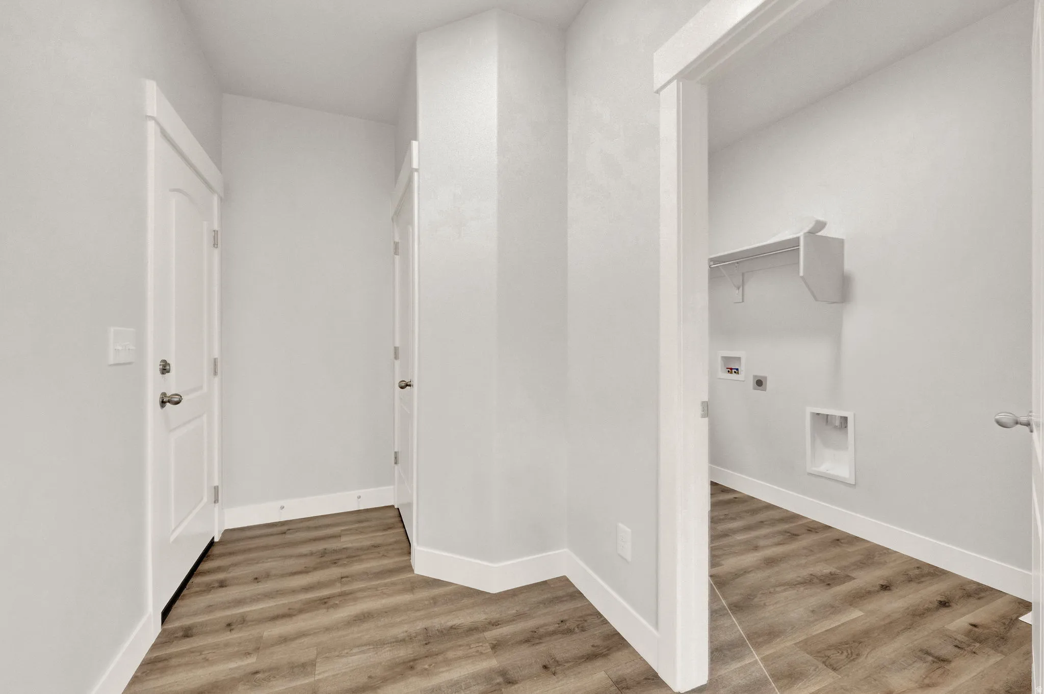 Utility room featuring wood-finish flooring, white walls, and bright white trim