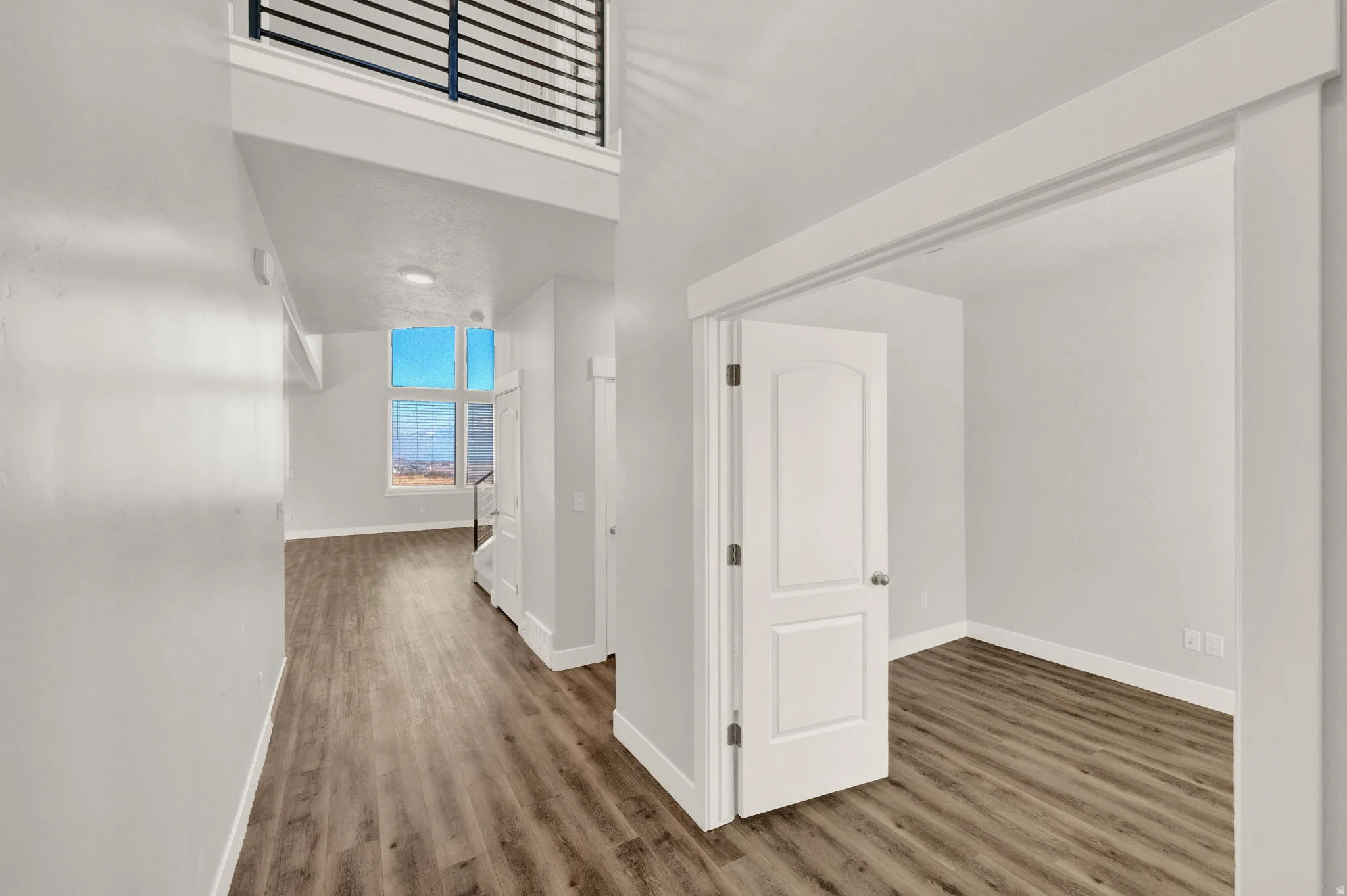 Open concept interior featuring wood-finish flooring, white trim, and a high ceiling