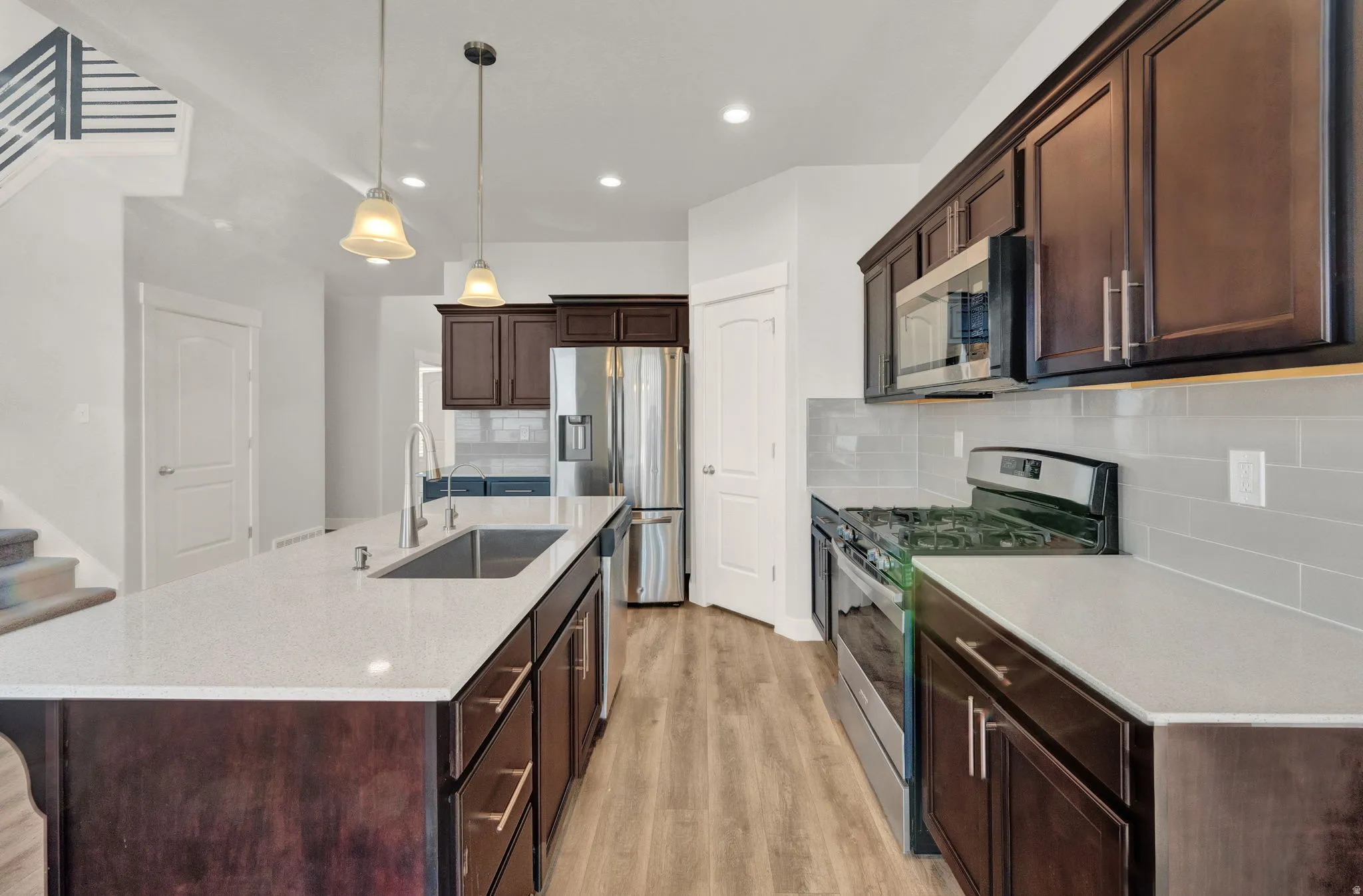 Kitchen featuring a large central island with an undermount sink and pendant lighting