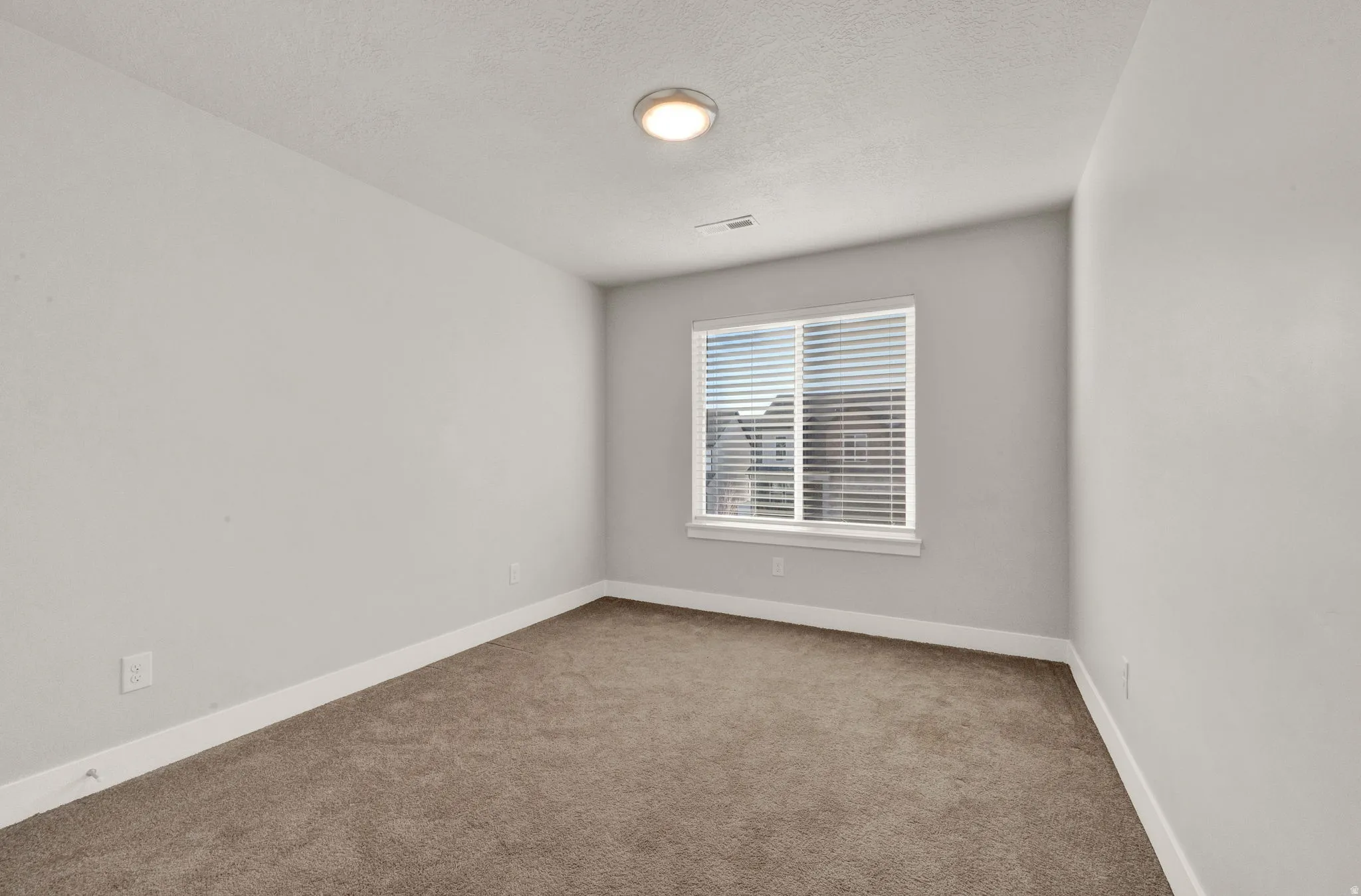 Bedroom featuring a window with horizontal blinds, neutral-toned carpeting, and a flush-mount ceiling light