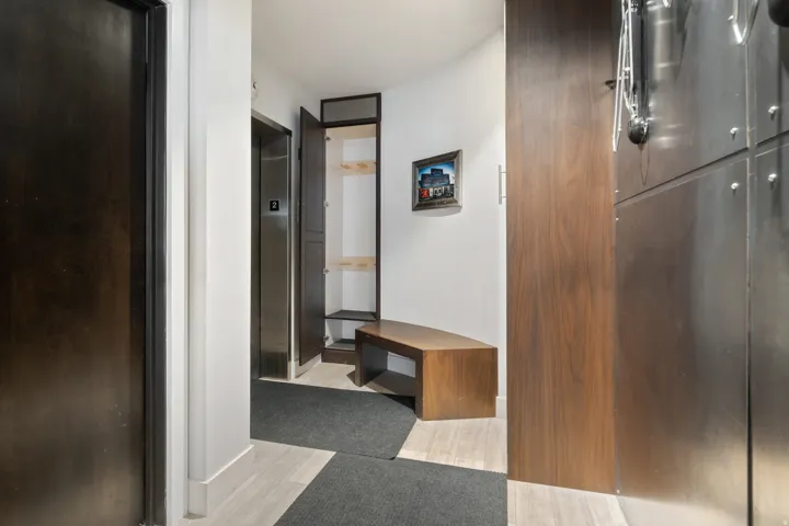 Entryway with light wood-finish flooring, dark wood doors, and a built-in storage bench