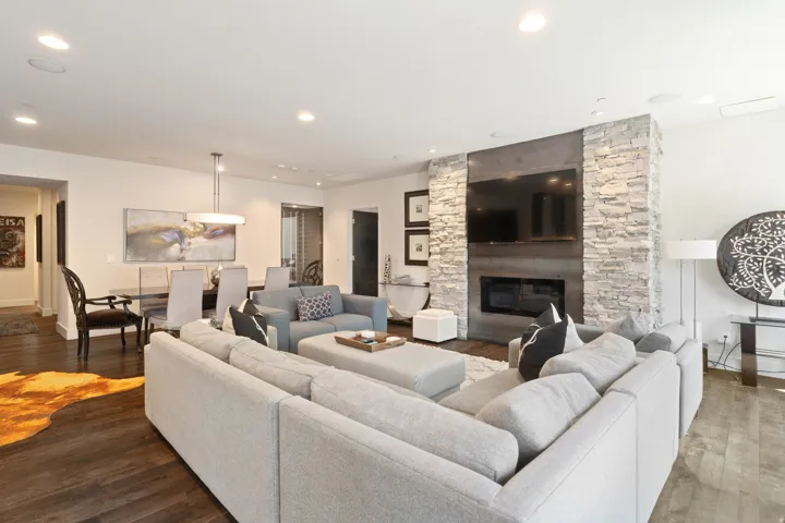 Spacious living area featuring dark wood-finish flooring, recessed lighting, and a stone-clad fireplace with an integrated media niche