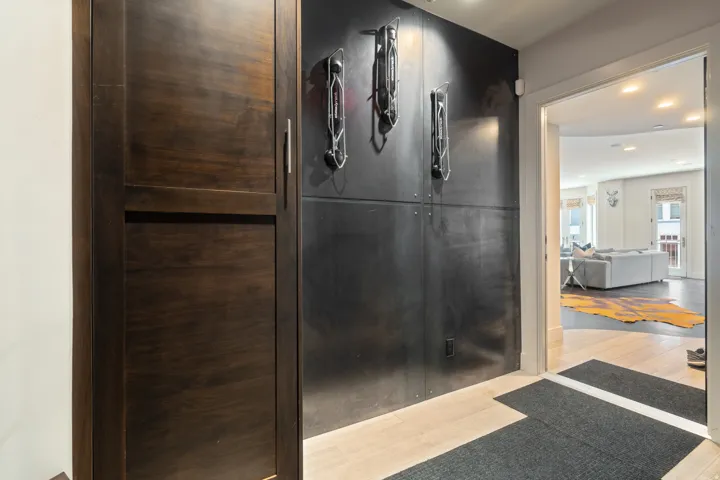Entryway featuring light wood-finish flooring, a dark built-in storage cabinet, and a dark accent wall