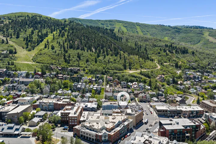 Town center setting with diverse architecture, surrounded by green hillsides and scattered evergreen trees