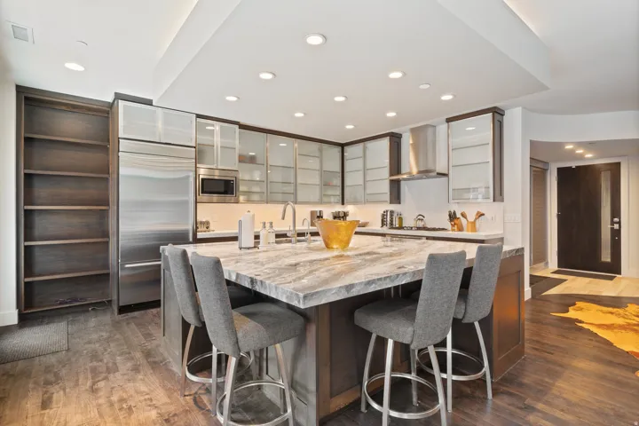 Modern kitchen featuring wood-finish flooring and a central island with a stone countertop