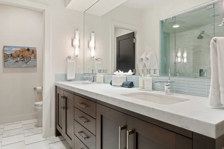 Dual sink vanity featuring dark wood cabinetry, integrated rectangular sinks, and a light-toned countertop