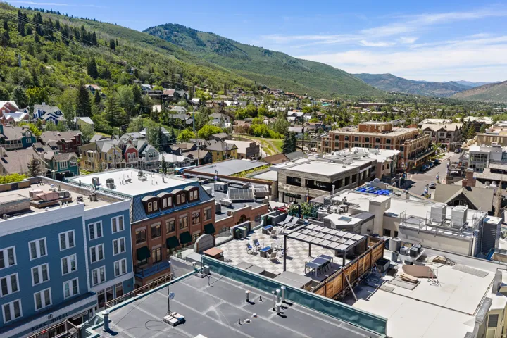 Panoramic view of a vibrant mountain town, featuring diverse architectural styles and extensive green hillsides