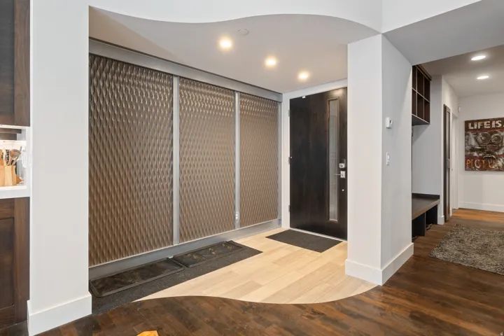 Entryway featuring a dark wood door with vertical glass insert, recessed lighting, and mixed-tone flooring