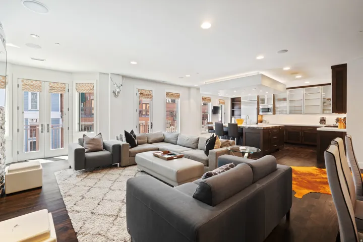 Open-concept living space with dark wood-finish flooring, recessed lighting, and balcony access through double French doors