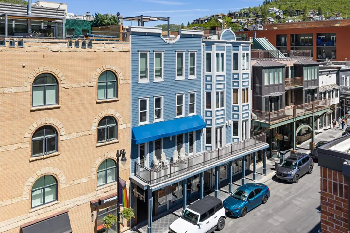 Multi-story building featuring blue siding, white trim, and a prominent blue awning