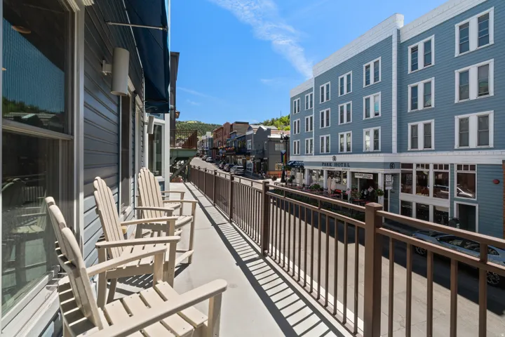 Balcony with metal railings overlooking a streetscape featuring commercial buildings with architectural details