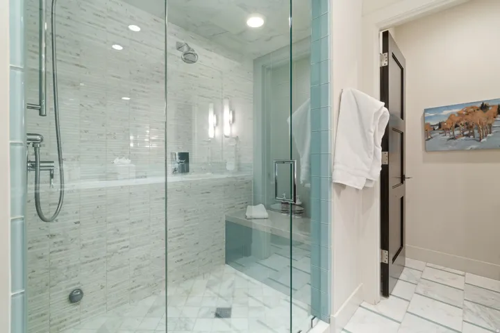 Glass-enclosed shower with horizontal tile detailing, a built-in bench, and recessed lighting