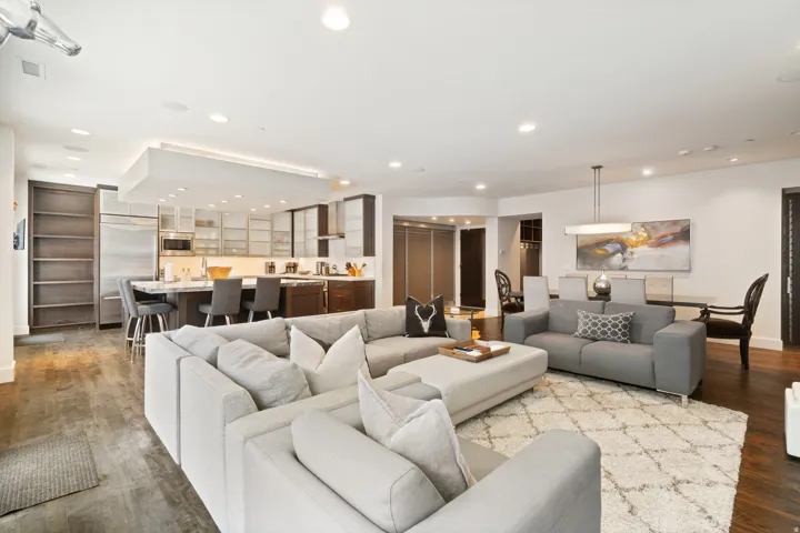 Expansive open-concept living area featuring dark wood-finish flooring, recessed lighting, and a kitchen island with seating