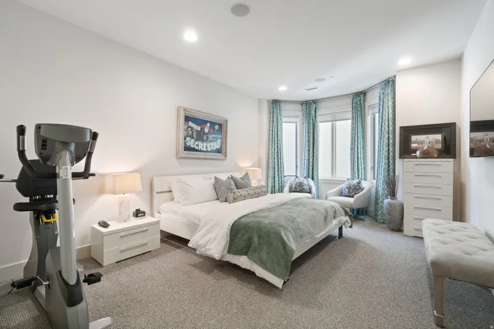 Spacious bedroom featuring a curved bay window with floor-to-ceiling drapery, recessed lighting, and a neutral carpeted floor
