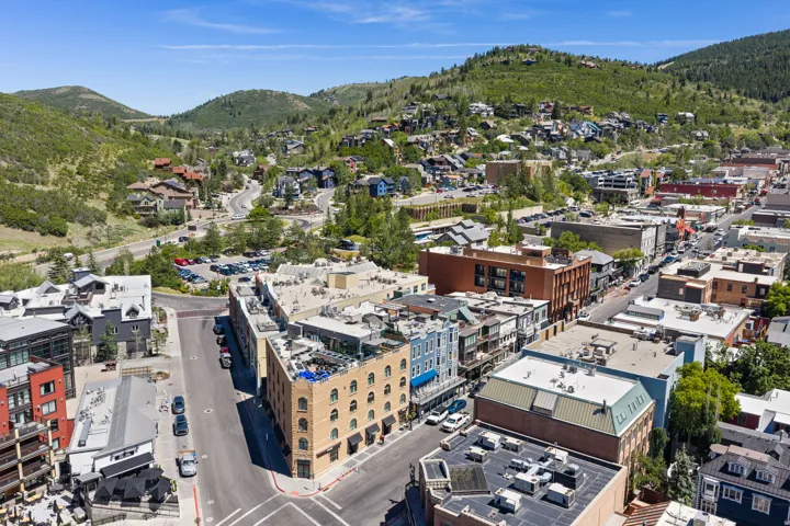 Aerial perspective showcasing a vibrant urban streetscape surrounded by verdant, tree-covered hillsides