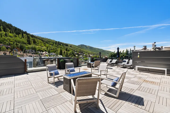 Expansive rooftop deck featuring modular wood-finish flooring, a built-in outdoor fire pit, and privacy screening