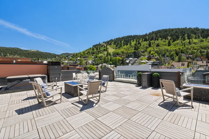 Rooftop deck featuring wood-finish tile flooring, a built-in hot tub, and a permanent fire pit