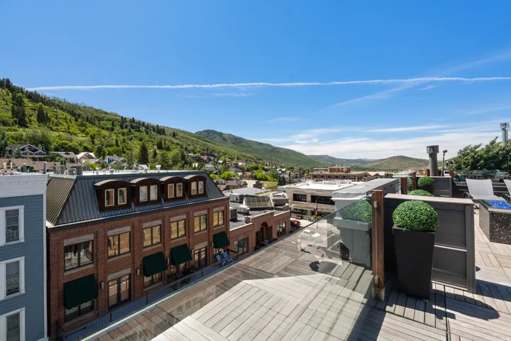 Rooftop deck featuring a glass railing, wood-finish flooring, and mountain scenery