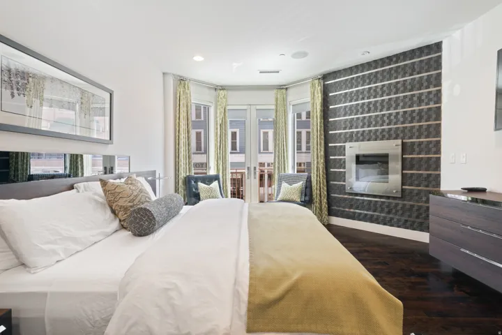 Bay windows with exterior access, dark wood-finish flooring, recessed lighting, and a wall-mounted fireplace with a decorative accent wall