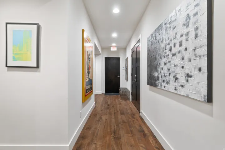 Hallway featuring wood-finish flooring, recessed lighting, white walls, and dark-paneled doors