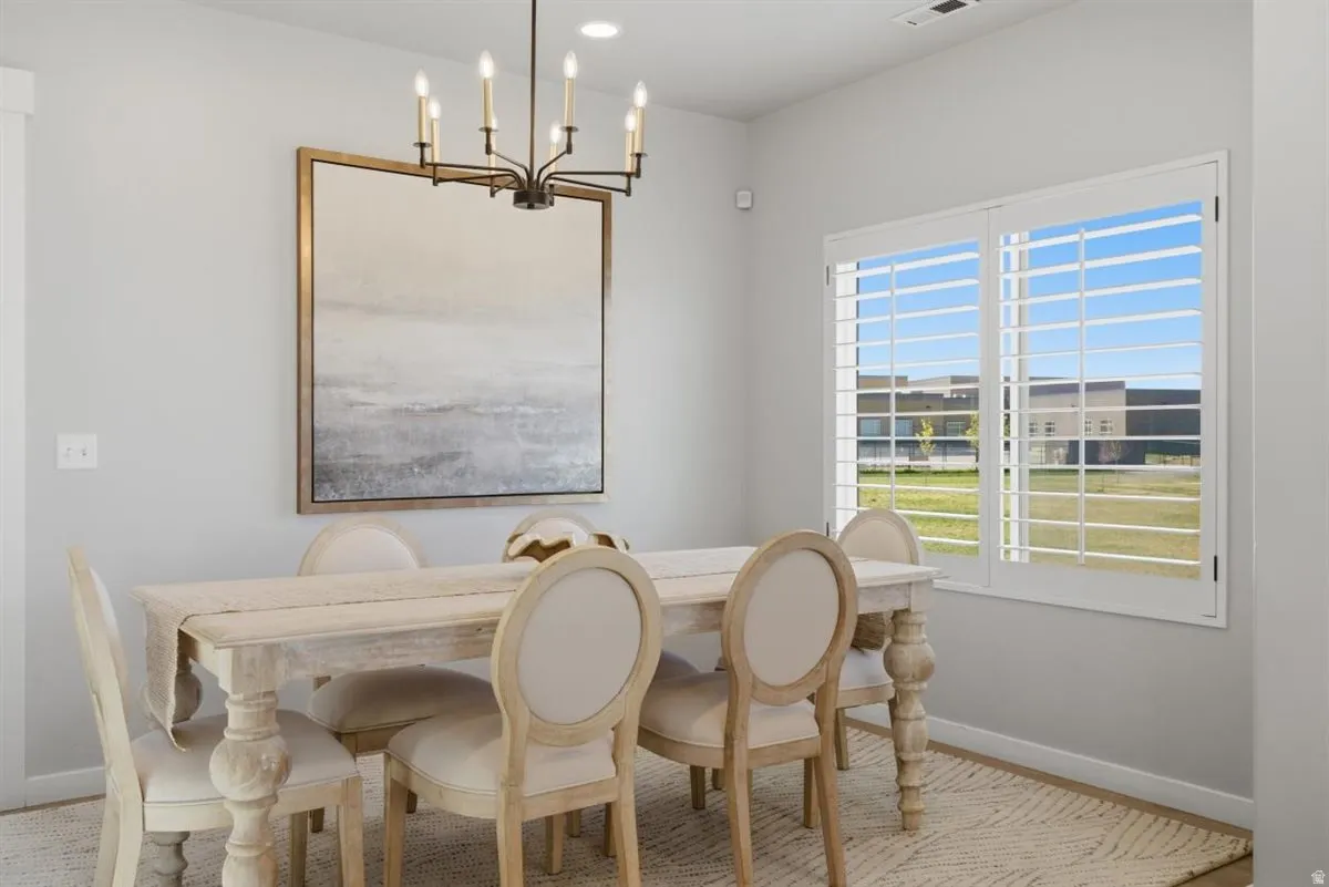 Dining space featuring a candelabra-style chandelier, light gray wall tones, and a large window with white plantation shutters