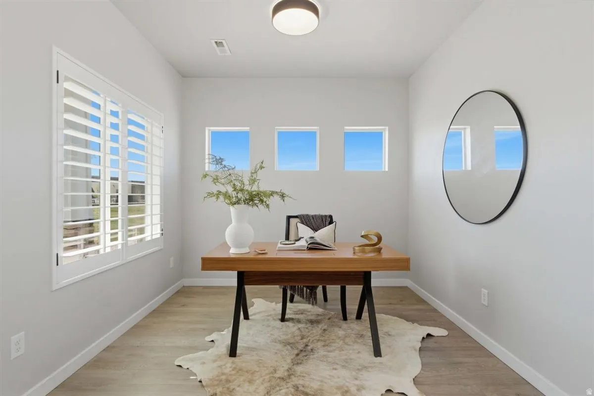 Neutral-toned room featuring a wood-finish flooring, white baseboards, and light gray walls