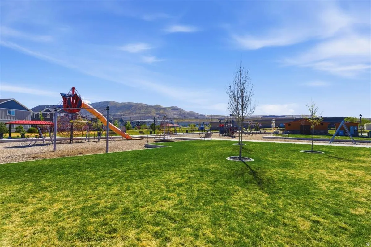 Expansive grassy area with a playground structure featuring slides and swings