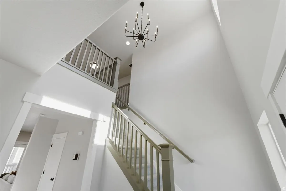Two-story entryway featuring a contemporary chandelier, light-toned walls, and a staircase with a light wood-finish railing