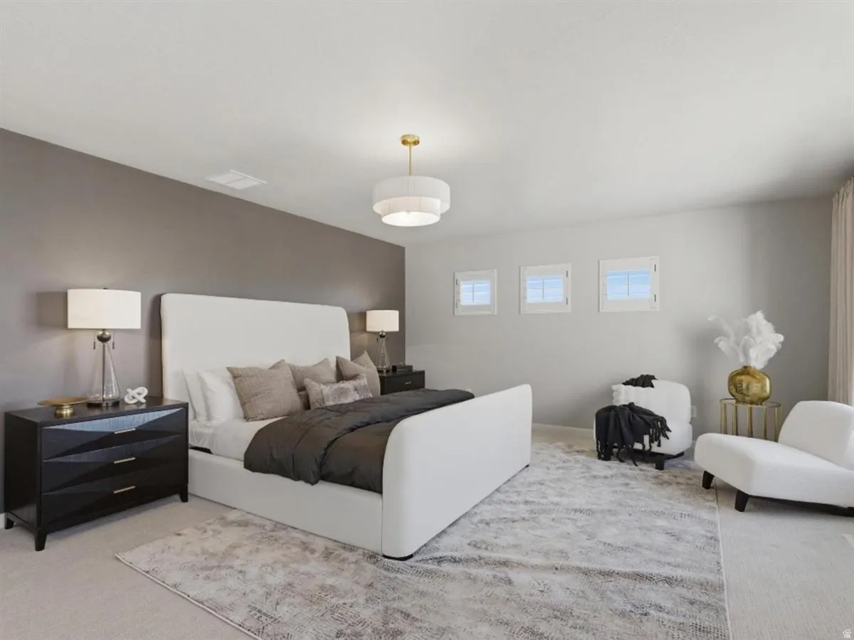Spacious bedroom featuring light-colored carpeting, a partial accent wall, three transom windows, and a ceiling-mounted light fixture