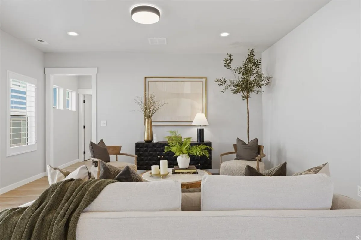 Spacious living area featuring light-toned walls, recessed lighting, and wood-finish flooring