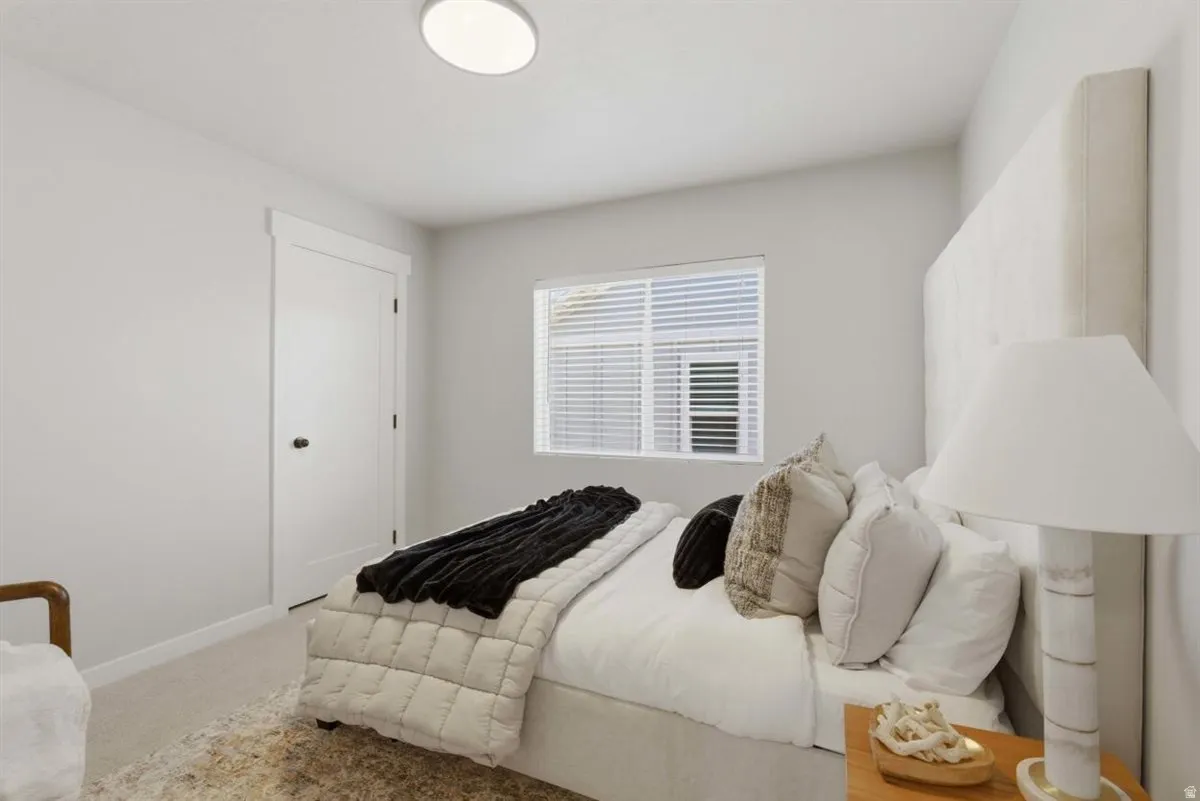 Bright bedroom with neutral wall tones and a single window featuring blinds