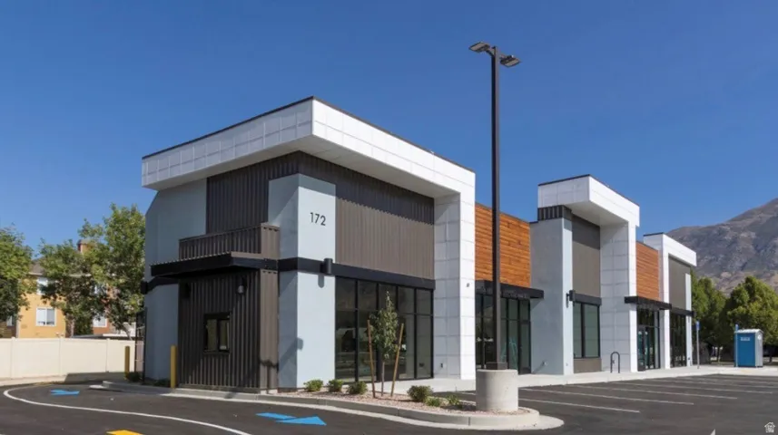 Contemporary commercial building featuring a multi-textured facade with vertical paneling, light-colored stone-look accents, and wood-finish detailing