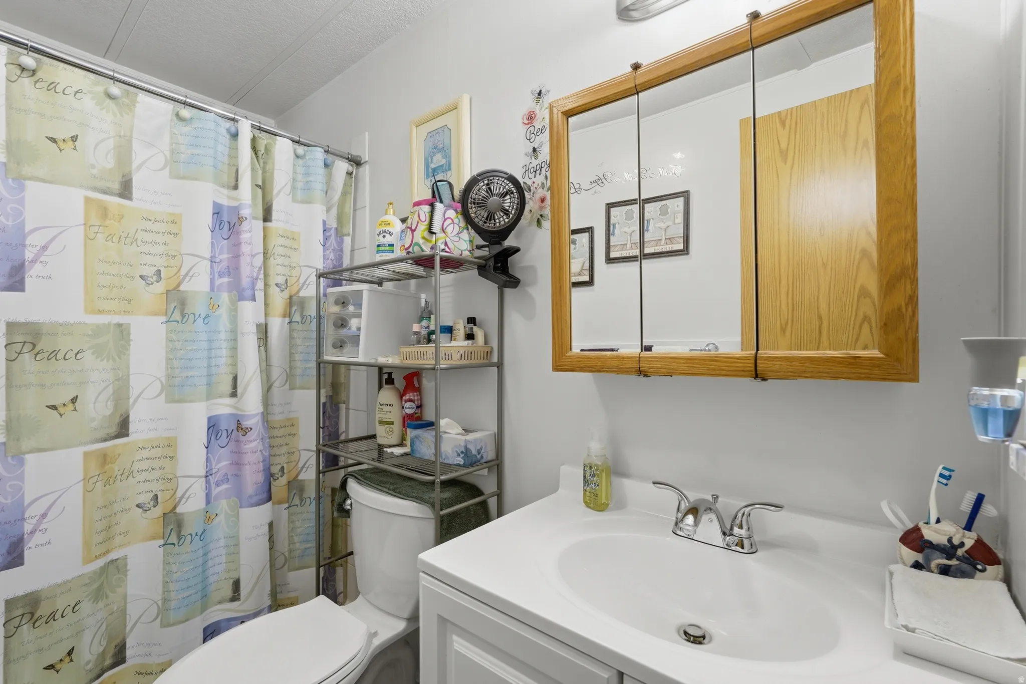 Bathroom featuring a white vanity with integrated sink, chrome faucet, and wood-framed mirrored medicine cabinet