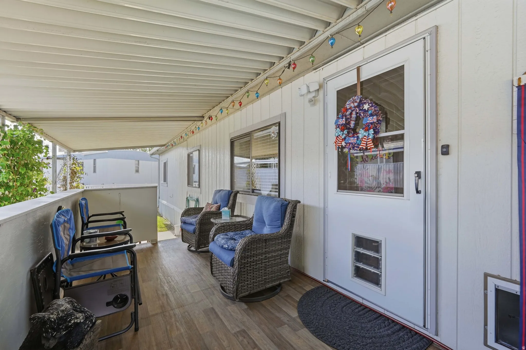 Covered outdoor porch featuring wood-finish flooring, white siding, and a white screen door