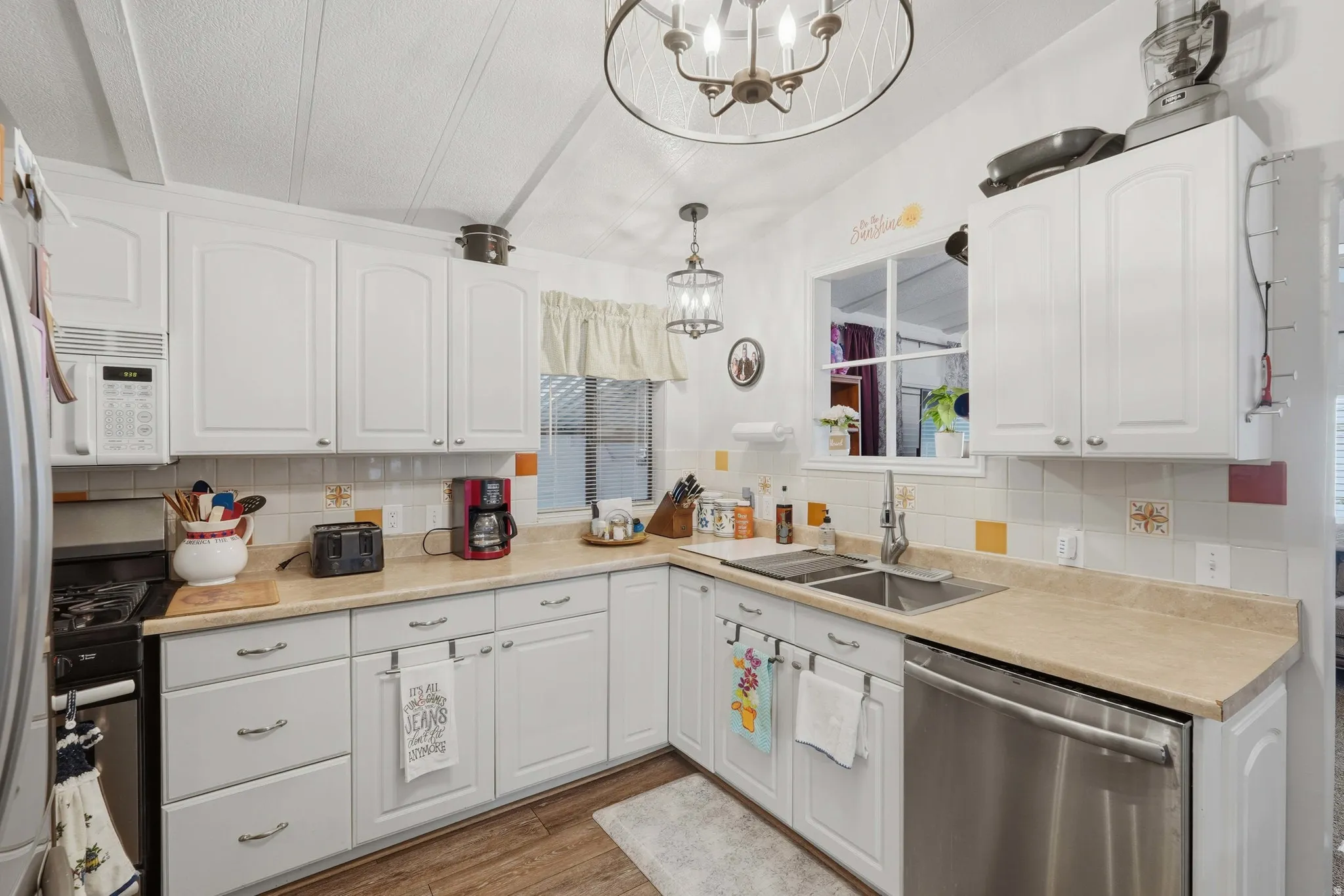 Kitchen featuring white cabinetry, light countertops, wood-finish flooring, and a stainless steel dishwasher