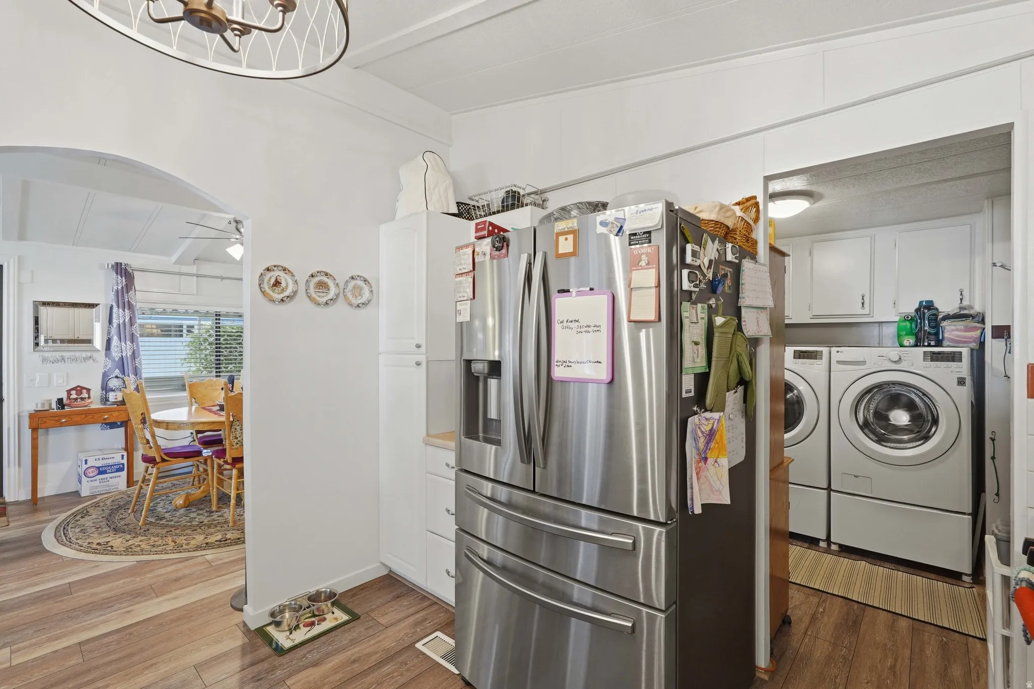 Kitchen area featuring wood-finish flooring, white cabinetry, and stainless steel appliances