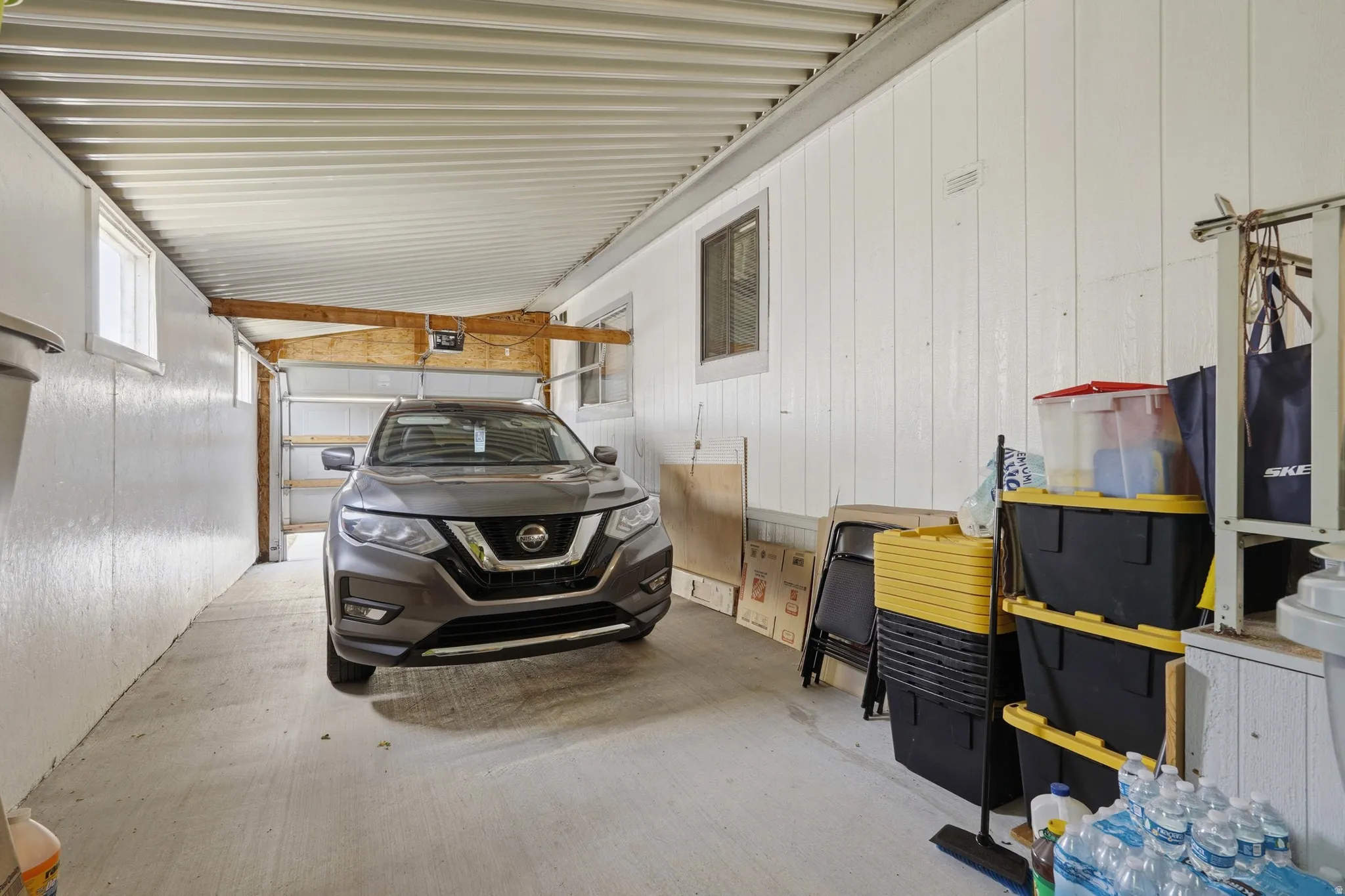 Carport with concrete flooring, wood beam structural elements, and a corrugated metal ceiling