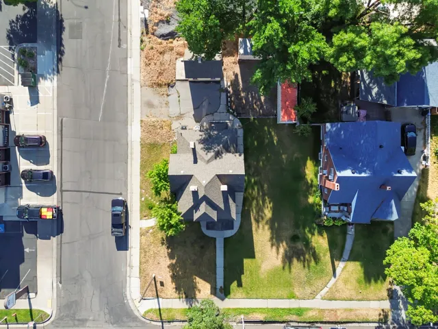 Gabled roofline residence featuring a manicured front lawn and mature trees