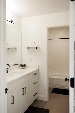 White vanity with black hardware, a rectangular undermount sink, and a light-toned countertop
