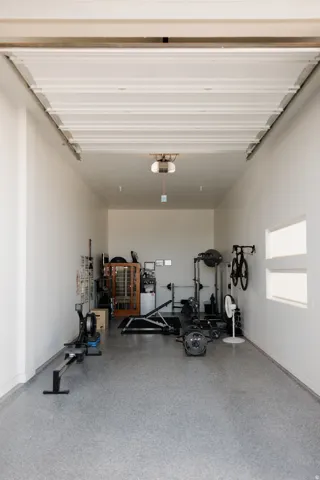 Spacious garage interior featuring a high ceiling, white painted walls, and an epoxy flake flooring system