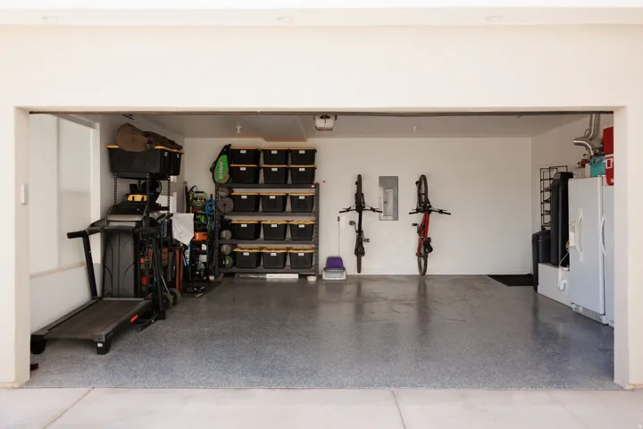 Spacious garage featuring a durable epoxy floor coating, white painted walls, and overhead lighting