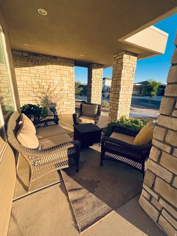 Covered patio featuring stone-clad pillars, recessed lighting, and a concrete floor