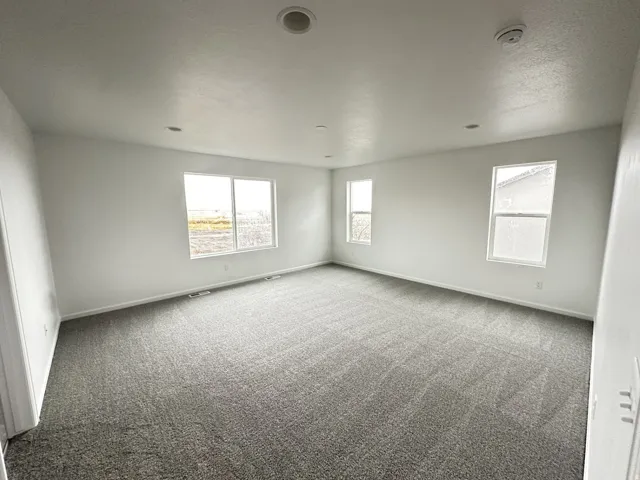 Spacious room featuring neutral walls, gray carpeting, recessed lighting, and multiple windows