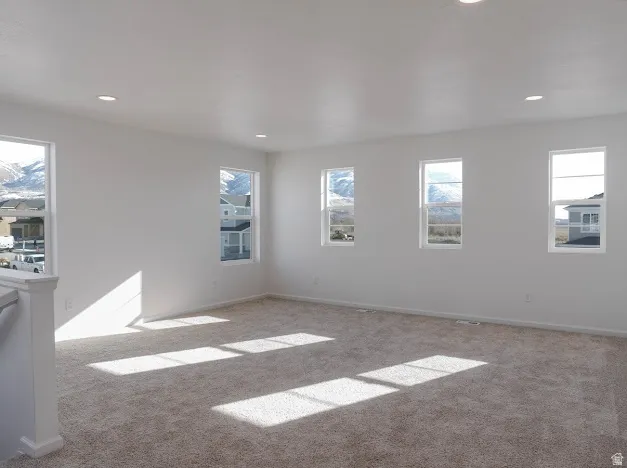 Spacious room featuring neutral carpeting, multiple windows with natural light, recessed lighting, and white trim
