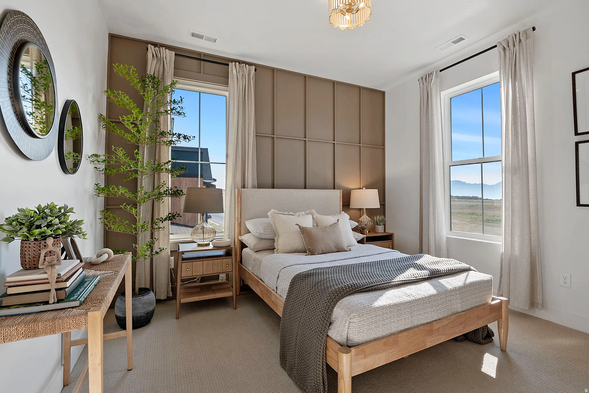 Bedroom featuring a paneled accent wall, two large windows, a ceiling-mounted light fixture, and carpet flooring