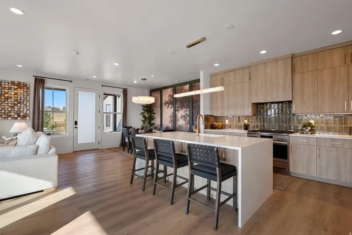 Open-concept kitchen and living area featuring wood-finish flooring, recessed lighting, and a white quartz island with integrated seating