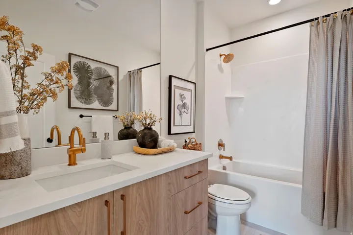 Contemporary bathroom featuring a wood-finish vanity with a white countertop and integrated sink