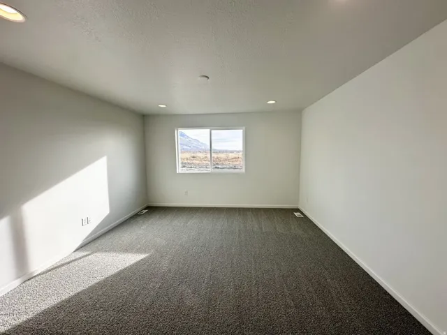 Recessed ceiling lighting, white painted walls, large window with mountain scenery, and grey carpet flooring