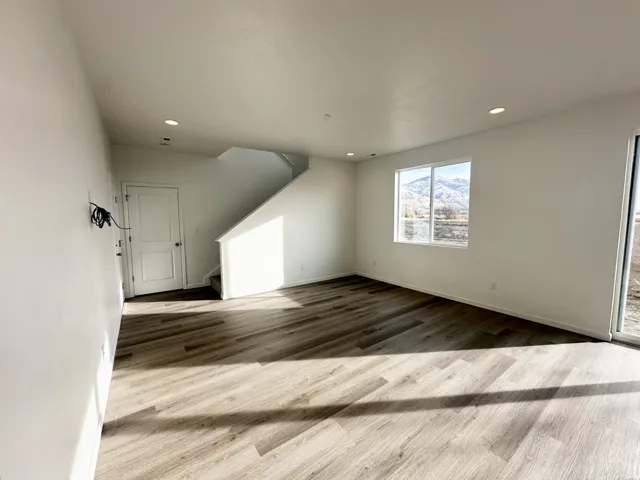 Recessed lighting, wood-finish flooring, white walls, large window, and sliding glass door