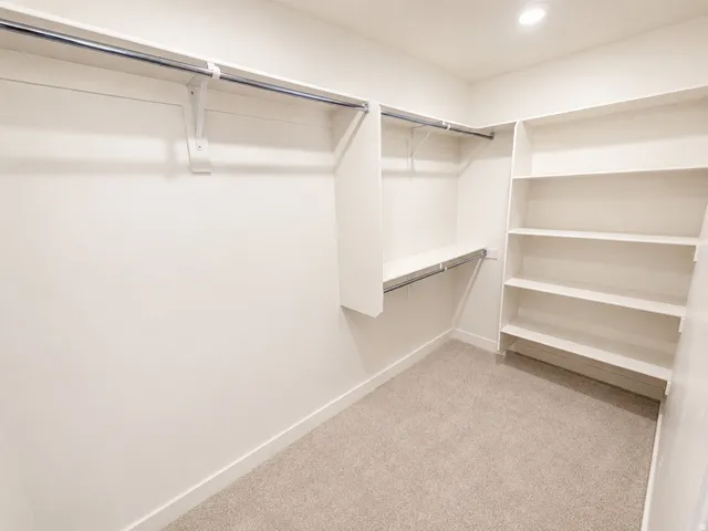 Walk-in closet featuring built-in shelving, multiple hanging rods, and recessed lighting